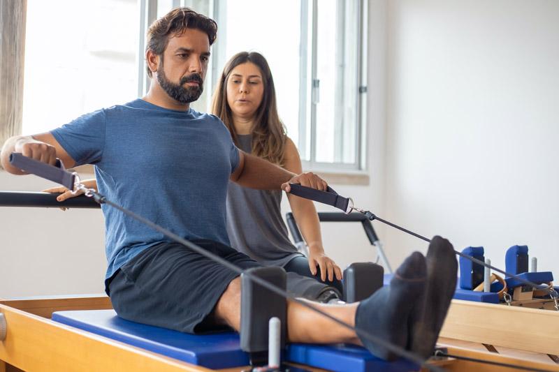 female physical therapy assistant standing behind man receiving assistance